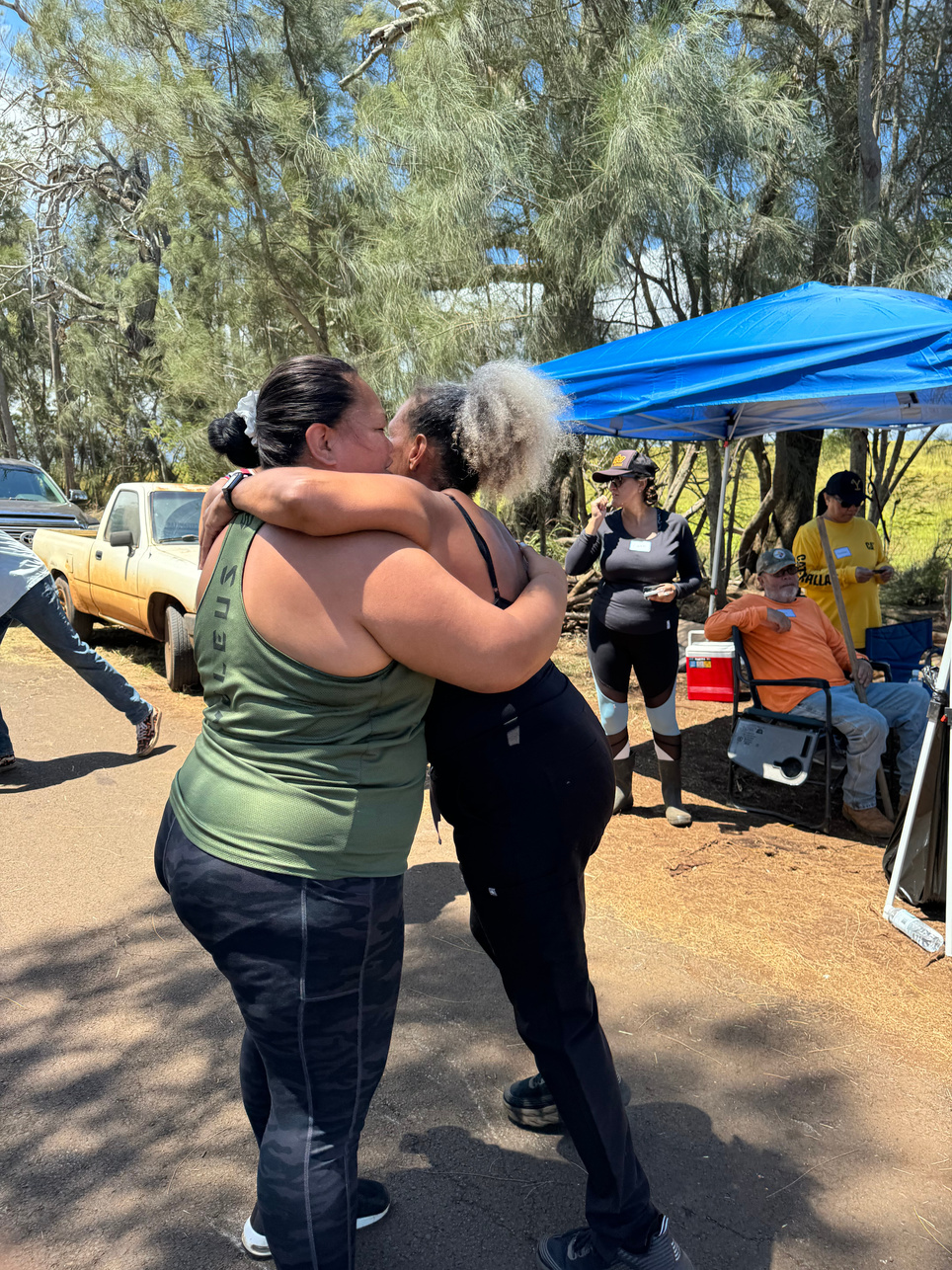 Two women embracing beside the volunteer rest area during the cleanup