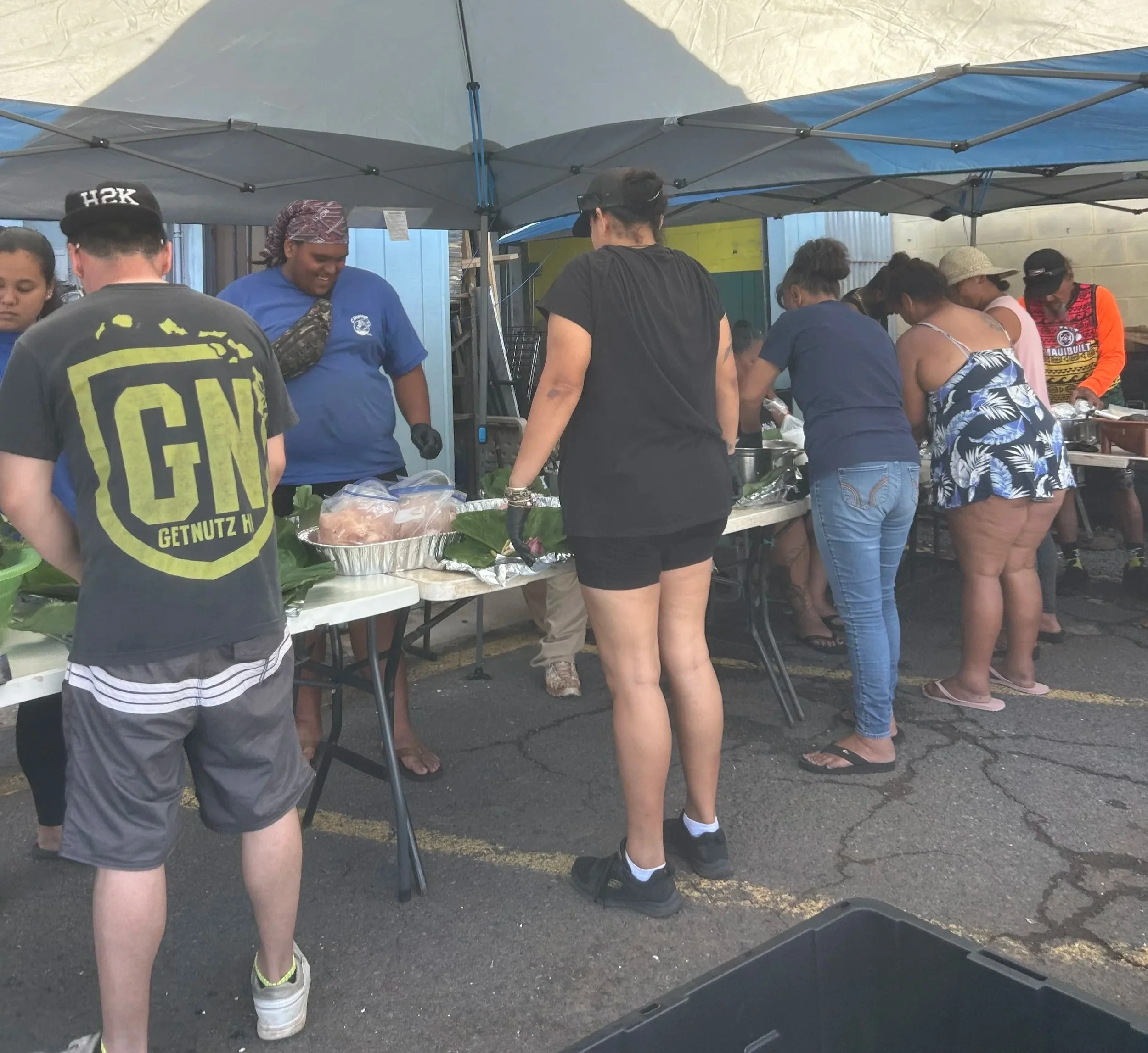 Community members preparing meals together beneath shade tents